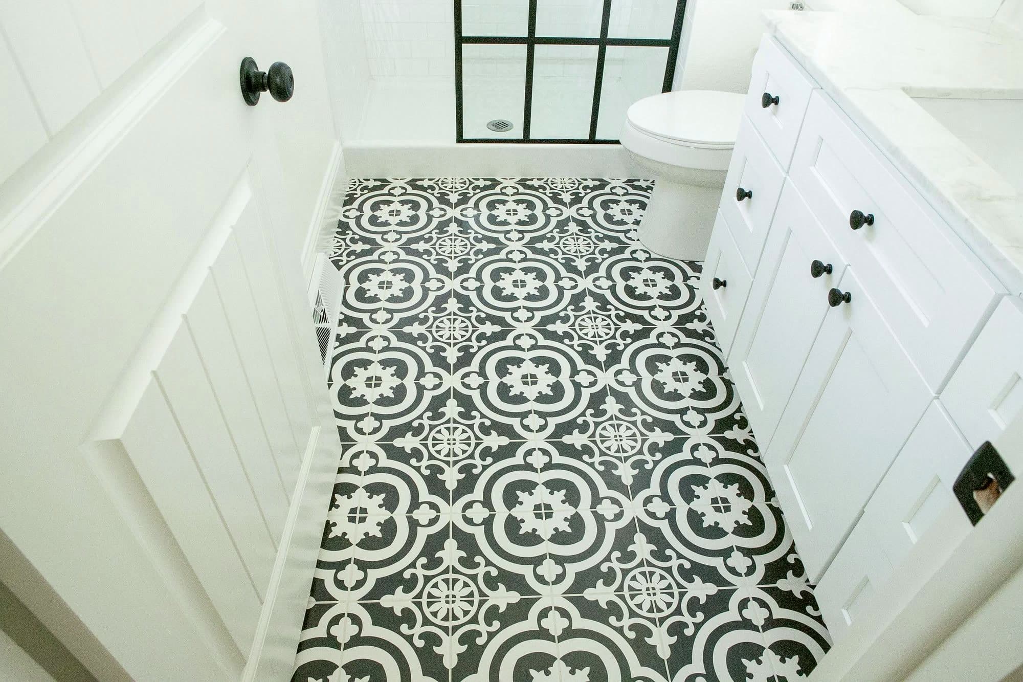 Bathroom remodel with patterned tile floor, black-framed shower glass, and white shaker vanity by Massey Contracting