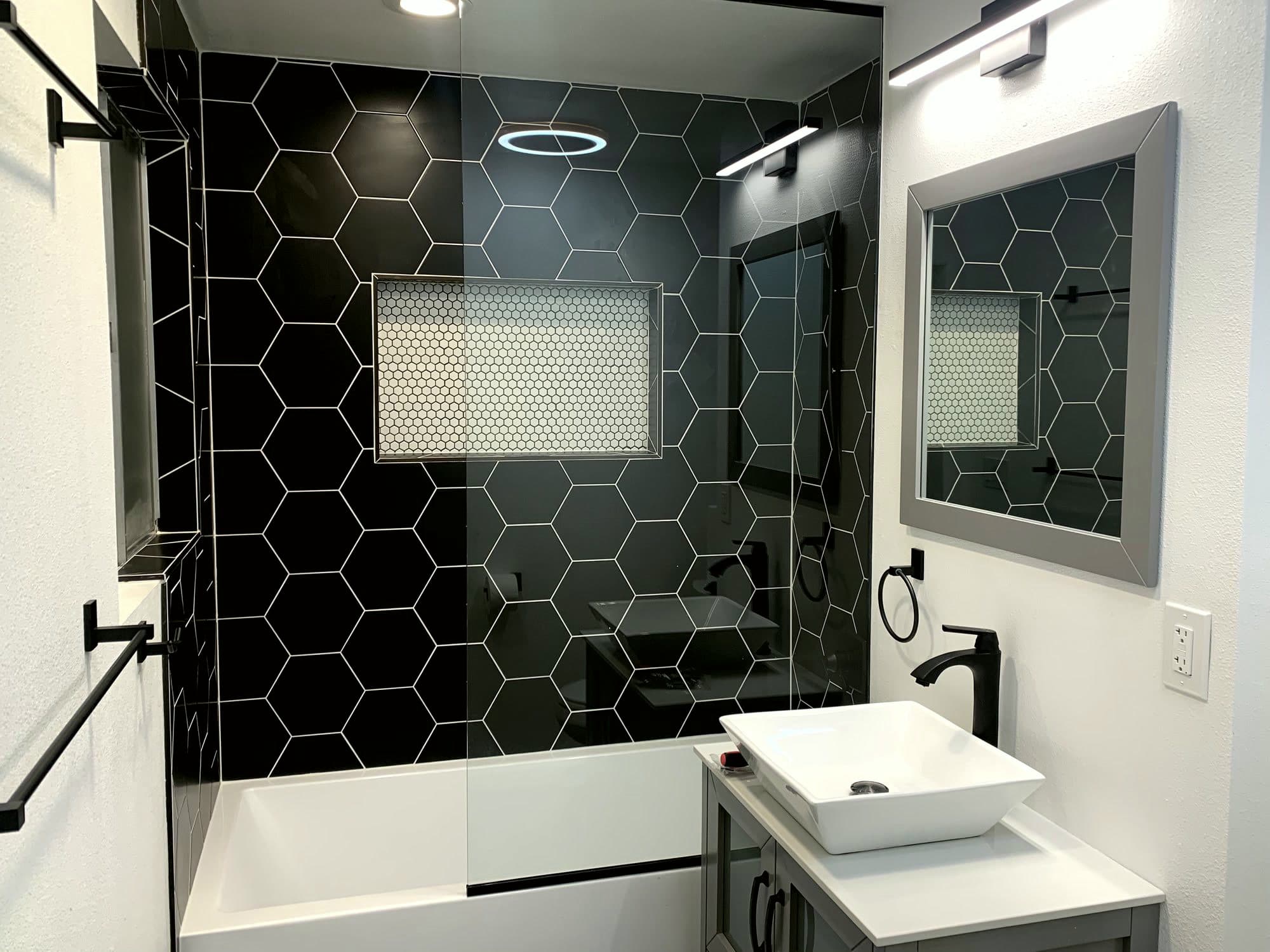 Bathroom remodel with black tile and matte black fixtures by Massey Contracting